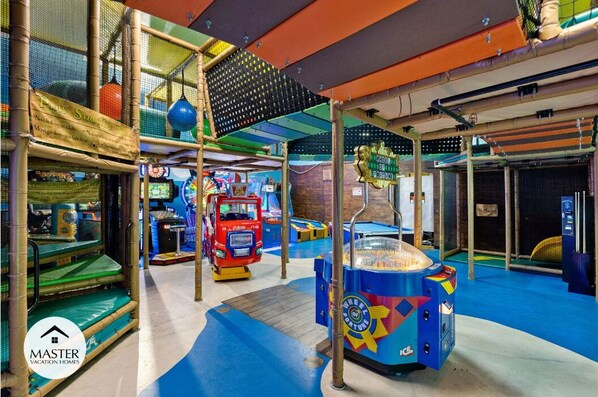 An indoor play area with climbing structures, a red toy truck, and a blue game machine.