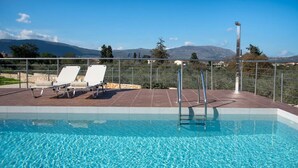 Une piscine à l’eau d’un bleu cristallin, deux chaises longues et une rambarde en métal.