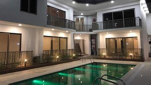 A modern multi-story building with a swimming pool, balconies, and exterior lighting. - Shorlets by First Bridgeford Homes (Lekki)