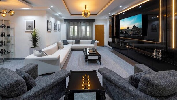 A modern living room with a sectional sofa, a coffee table, and a large flat-screen TV. - Shorlets by First Bridgeford Homes (Lekki)