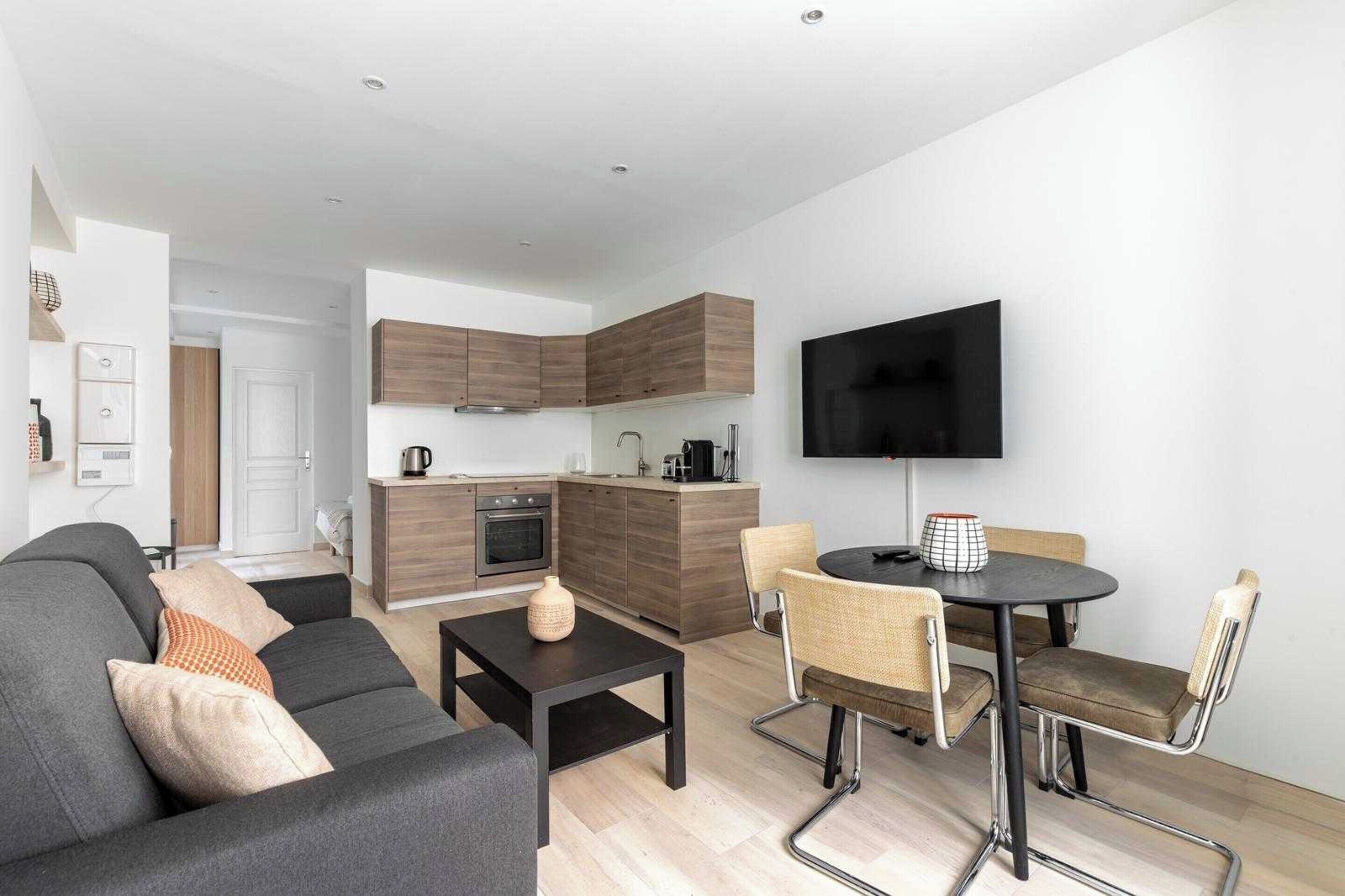 Egy modern apartman, amely nappalival, kis konyhasarokkal és étkezővel rendelkezik.