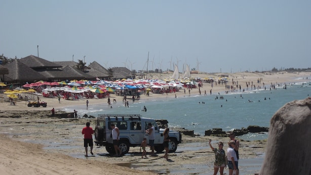 Una spiaggia con ombrelloni, un buggy da sabbia e persone vicino all'acqua.