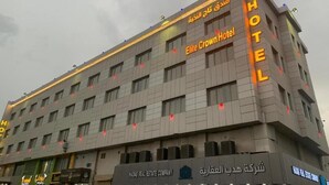 A hotel building with multiple floors, a prominent sign for the Elite Crown Hotel, and a sign for MADRAS REAL ESTATE COMPANY.