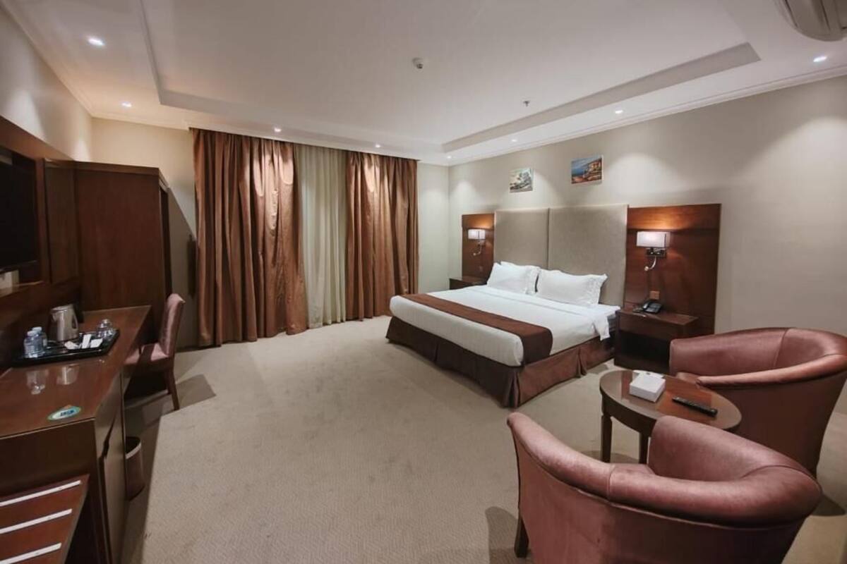 A hotel room with a bed, a desk, a chair, and a television.