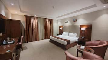 A hotel room with a bed, a desk, a chair, and a television.