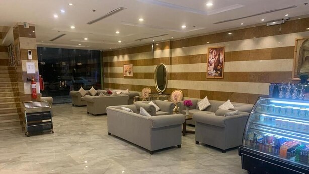 A hotel lobby with a marble floor, sofas, a glass display case, and a fire extinguisher.
