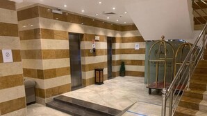 A lobby with striped walls, a staircase, and an elevator.