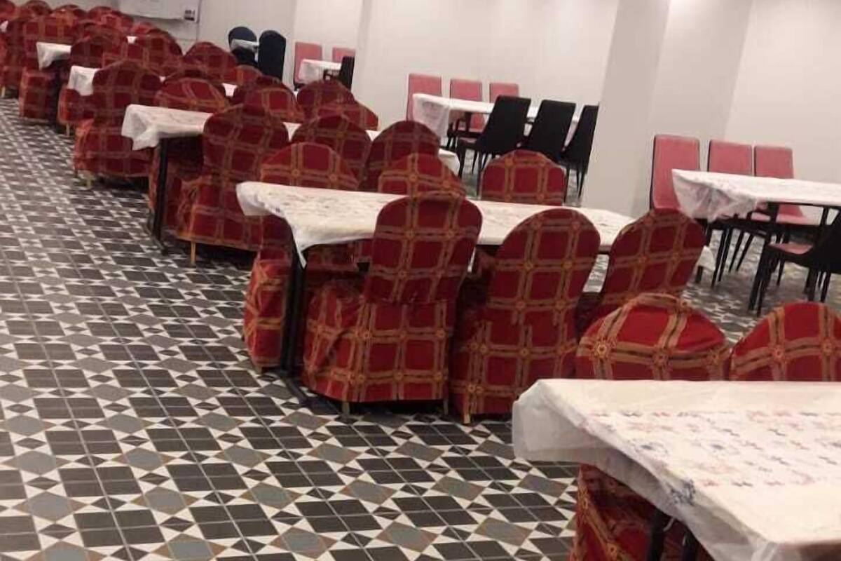 A conference room with rows of tables and chairs, patterned floor tiles, and recessed ceiling lighting.