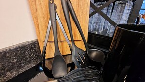 Uma bancada de cozinha com diversos utensílios, incluindo um batedor de arame, uma concha e uma espátula.