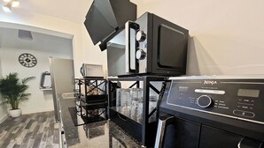 Uma cozinha com micro-ondas embutido, máquina de café e um relógio na parede.
