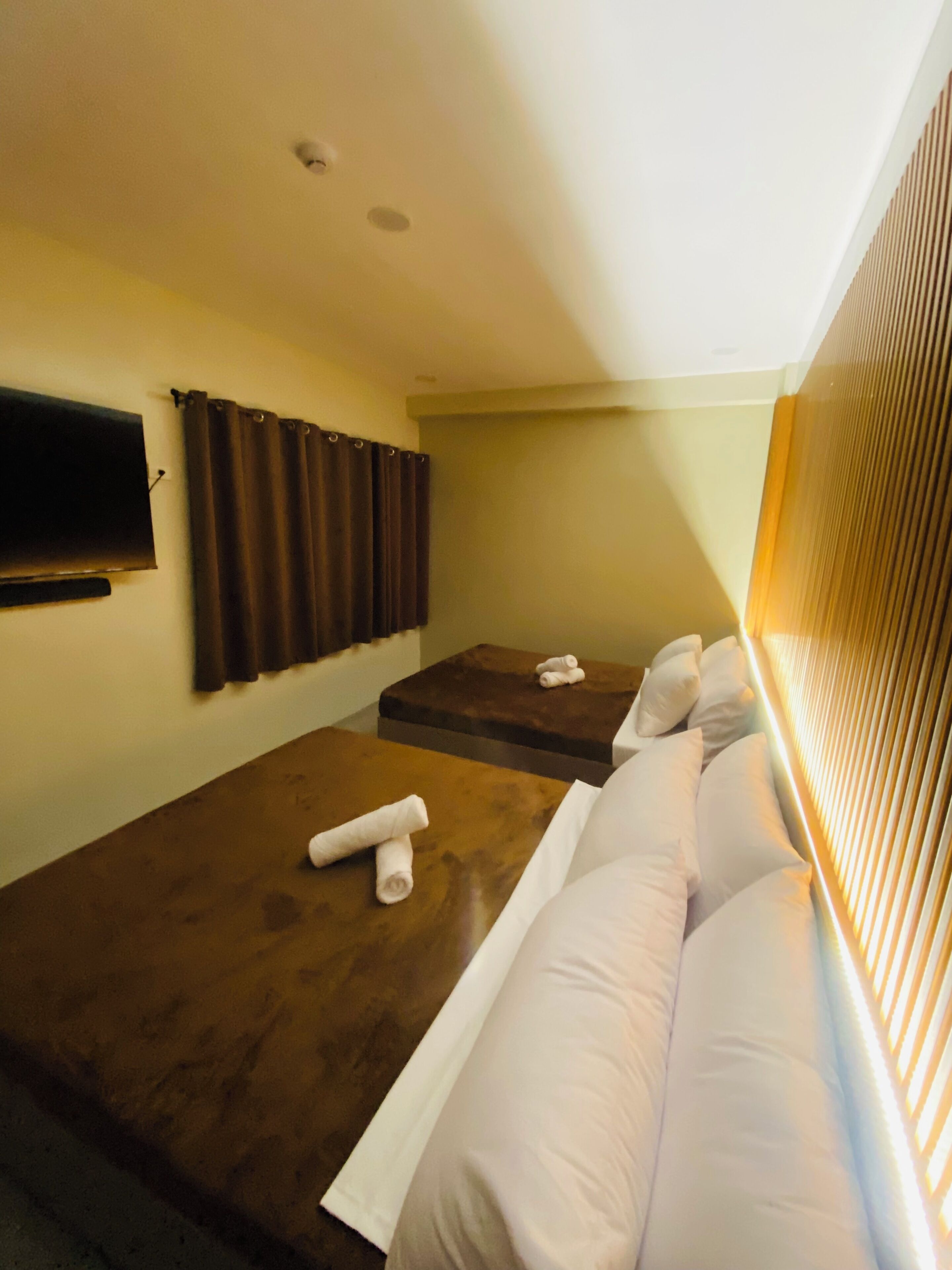 A room with a massage table, a sofa, and a TV mounted on the wall.