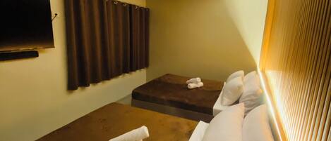 A room with a massage table, a sofa, and a TV mounted on the wall.