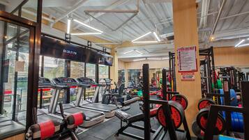 Un gimnasio con cintas de correr, máquinas de pesas y pesas sueltas.