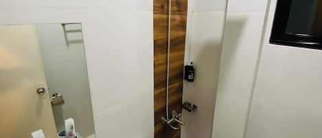 A modern bathroom with a glass sink, white toilet, and a shower with a wooden accent wall.