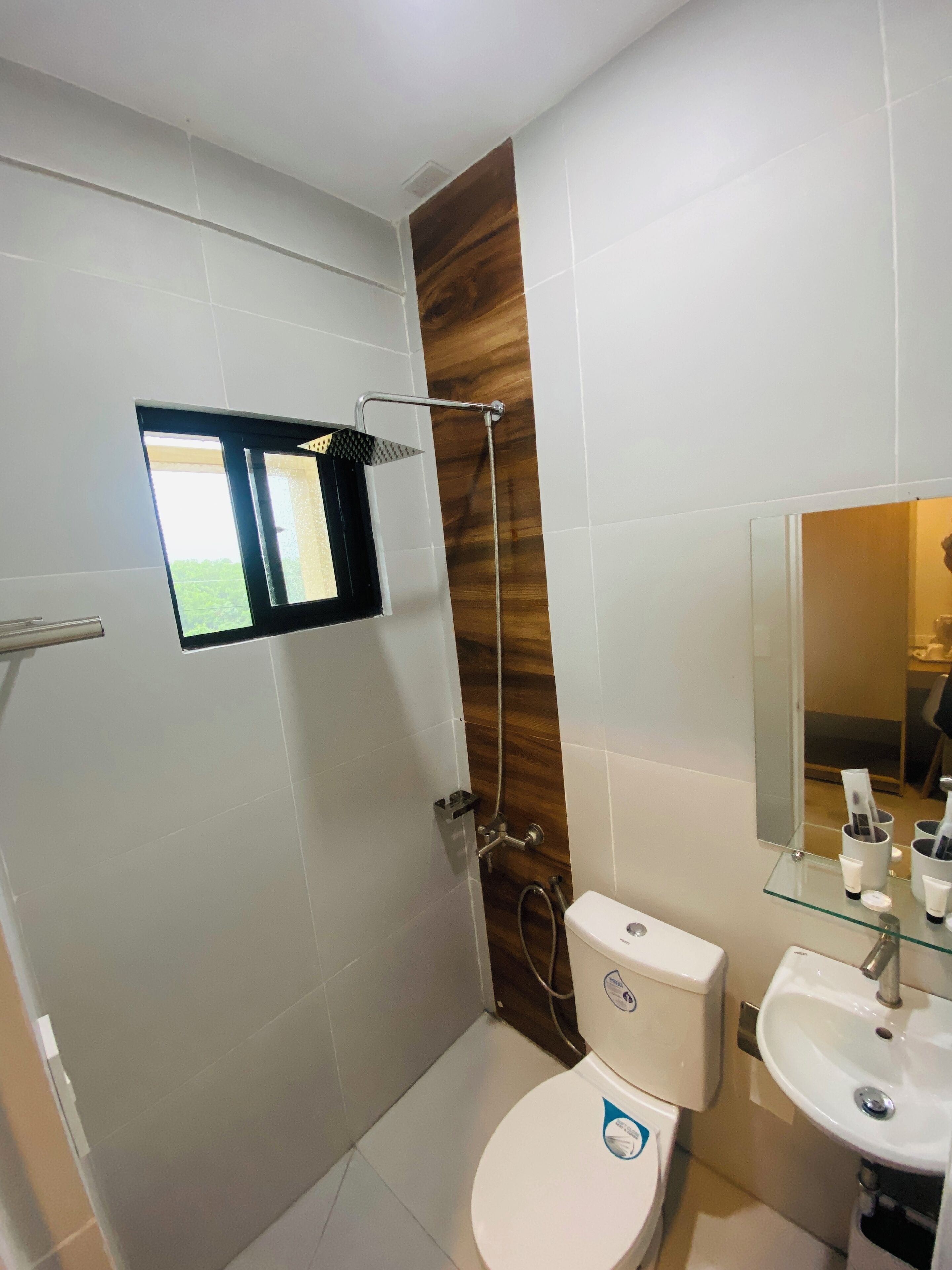 Een moderne badkamer met douche, toilet en wastafel.