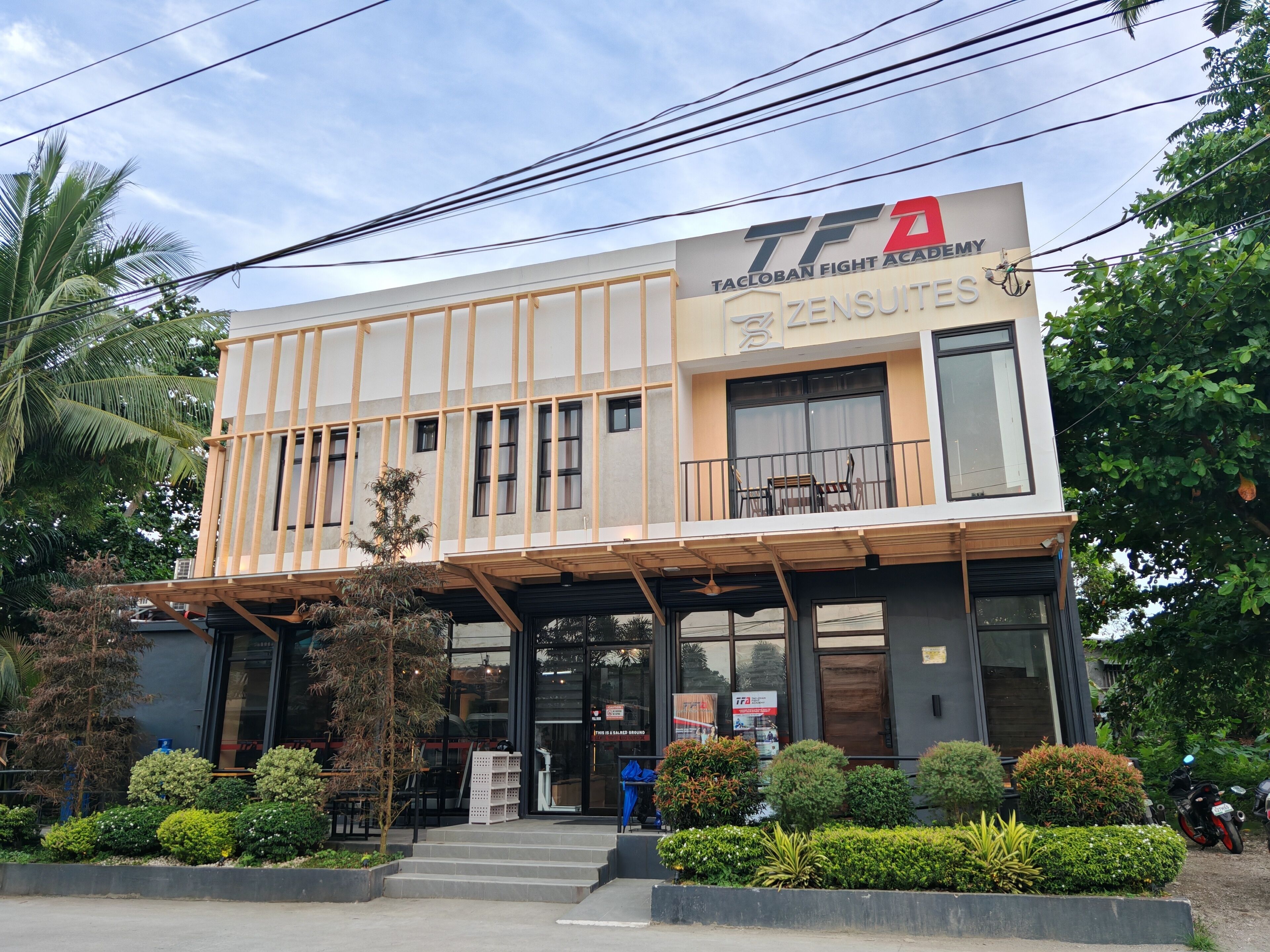 A building with a sign for 'Tacloban Fight Academy' and 'Zensuites'.