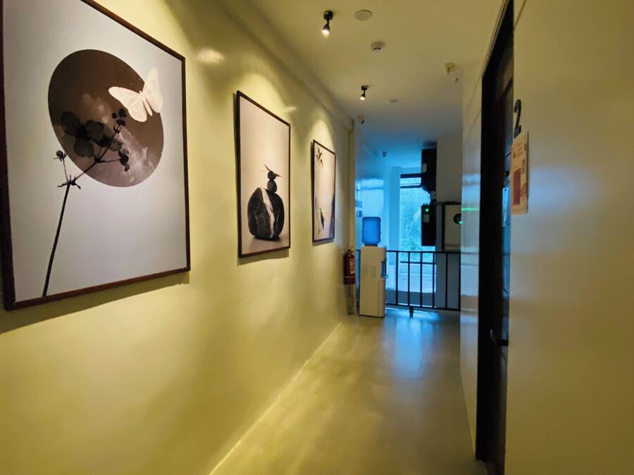 A hallway with framed artwork on the walls, a fire extinguisher, and a door at the end.