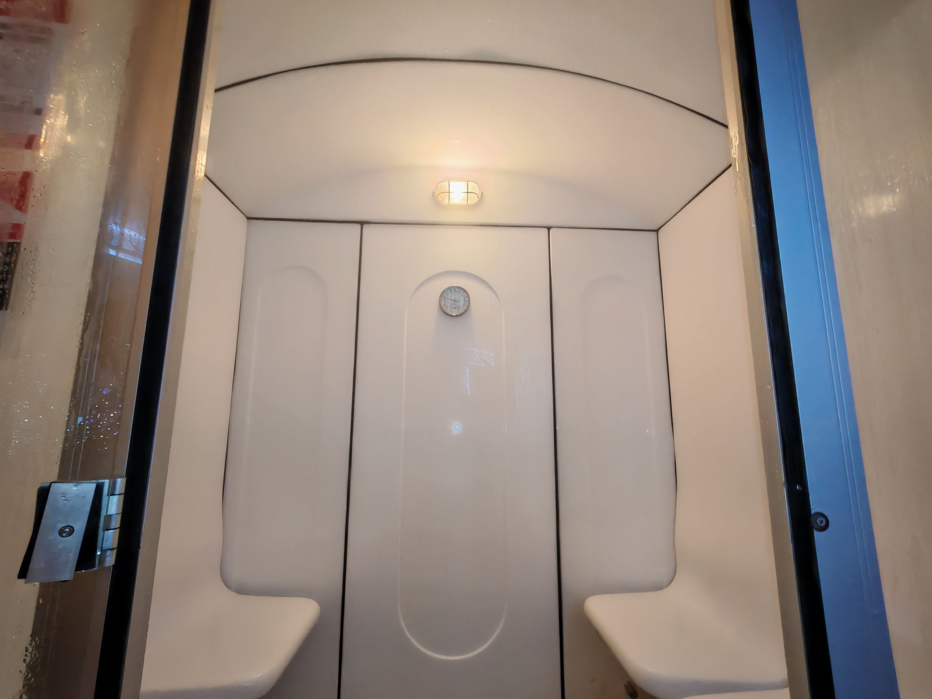 A compact, modern restroom with a curved ceiling and two toilet stalls.