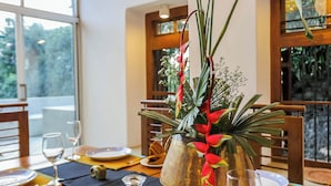 A dining table set with plates, cutlery, and a centerpiece of green foliage and red flowers. - Margossa Residence Kandy - Two Bedroom Design Villa (Kandy)