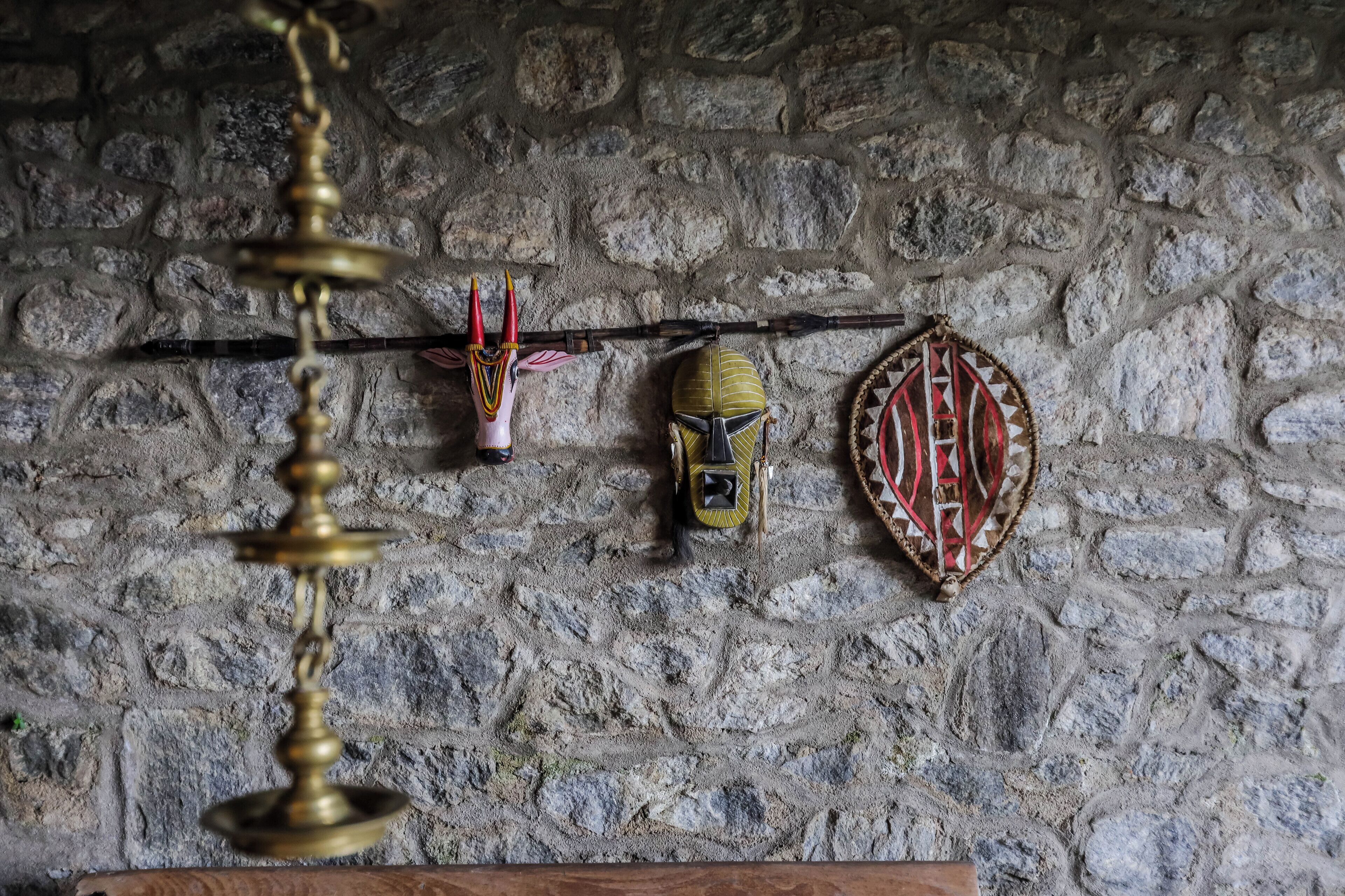 A stone wall with three masks hanging on it.
