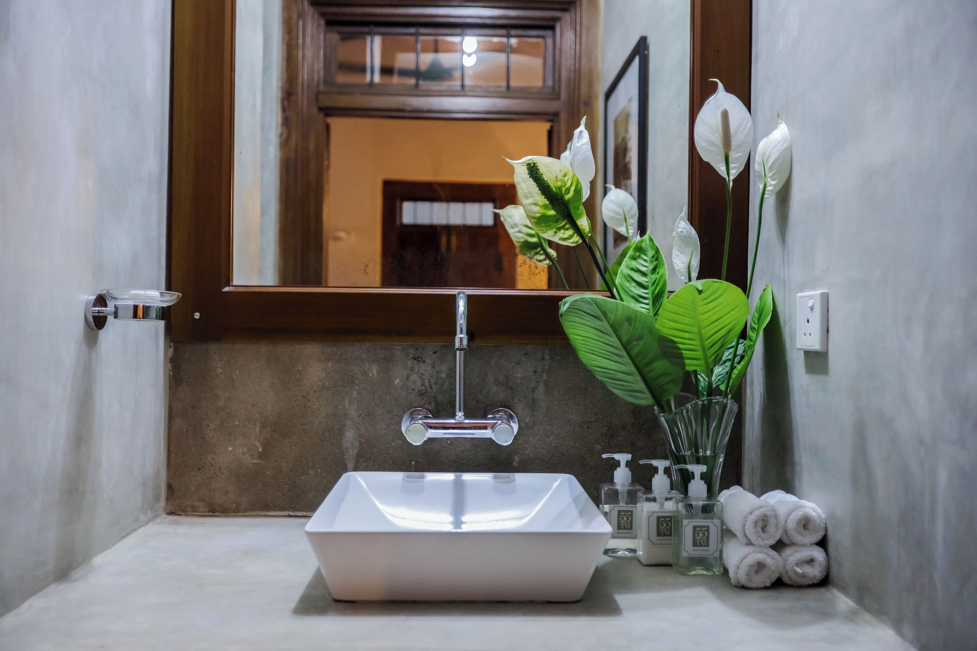 A bathroom with a white sink, a mirror, and a window above the sink.