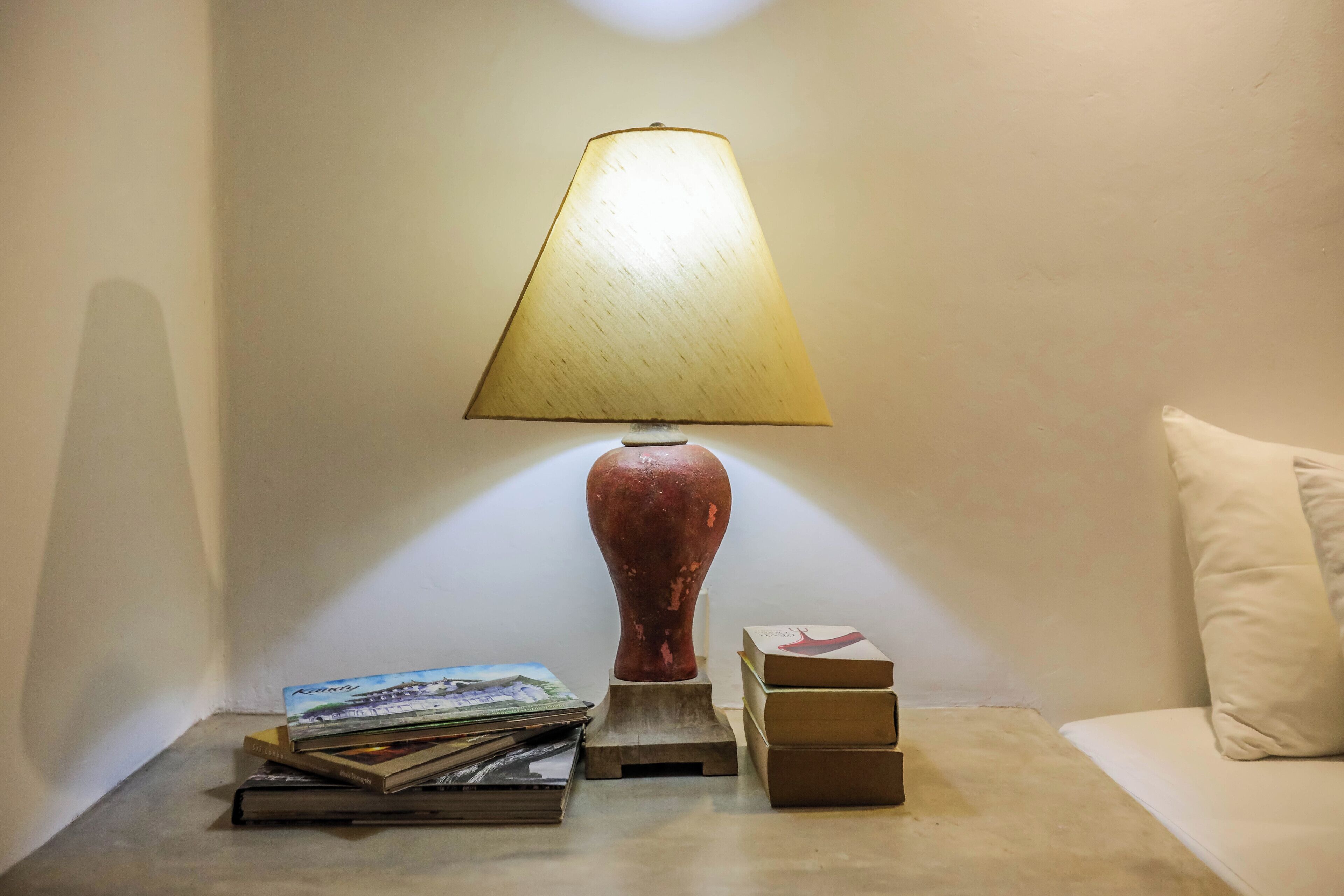 A bedside table with a lamp, books, and a small sculpture.