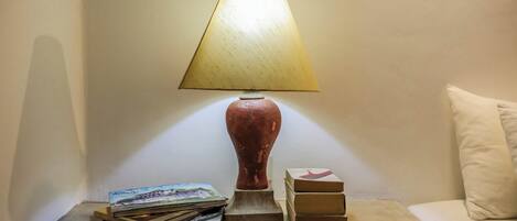 A bedside table with a lamp, books, and a small sculpture.