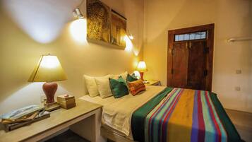 Quarto de hotel bem arrumado com cama, luminárias de cabeceira, mesa de cabeceira e um quadro na parede.