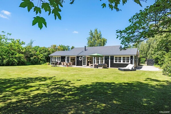 Une maison dotée d’un patio couvert, d’une pelouse et d’un garage.
