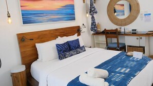 A neatly arranged hotel room with a bed, a desk, and a large painting of a sunset. - Jara Beach Resort (Lekki)