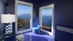 A balcony with a blue chair, a table with a lamp, and a view of the sea and mountains. - Villa Blue Capri in Massa Lubrense (Massa Lubrense)