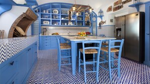 A kitchen with blue cabinetry, a central island with chairs, and a built-in brick oven. - Villa Blue Capri in Massa Lubrense (Massa Lubrense)