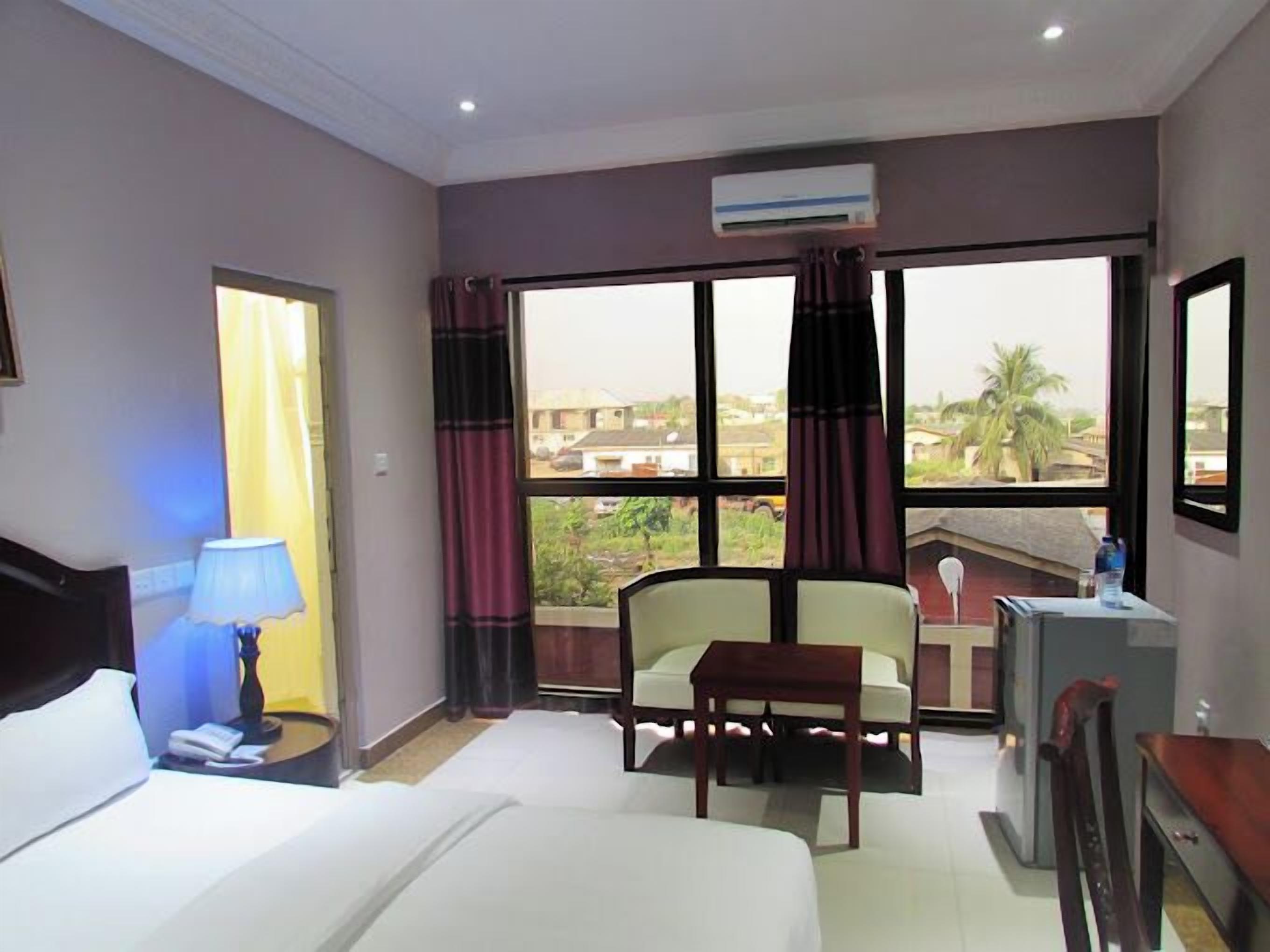 Habitación de hotel con cama, escritorio, una silla y vistas al exterior.