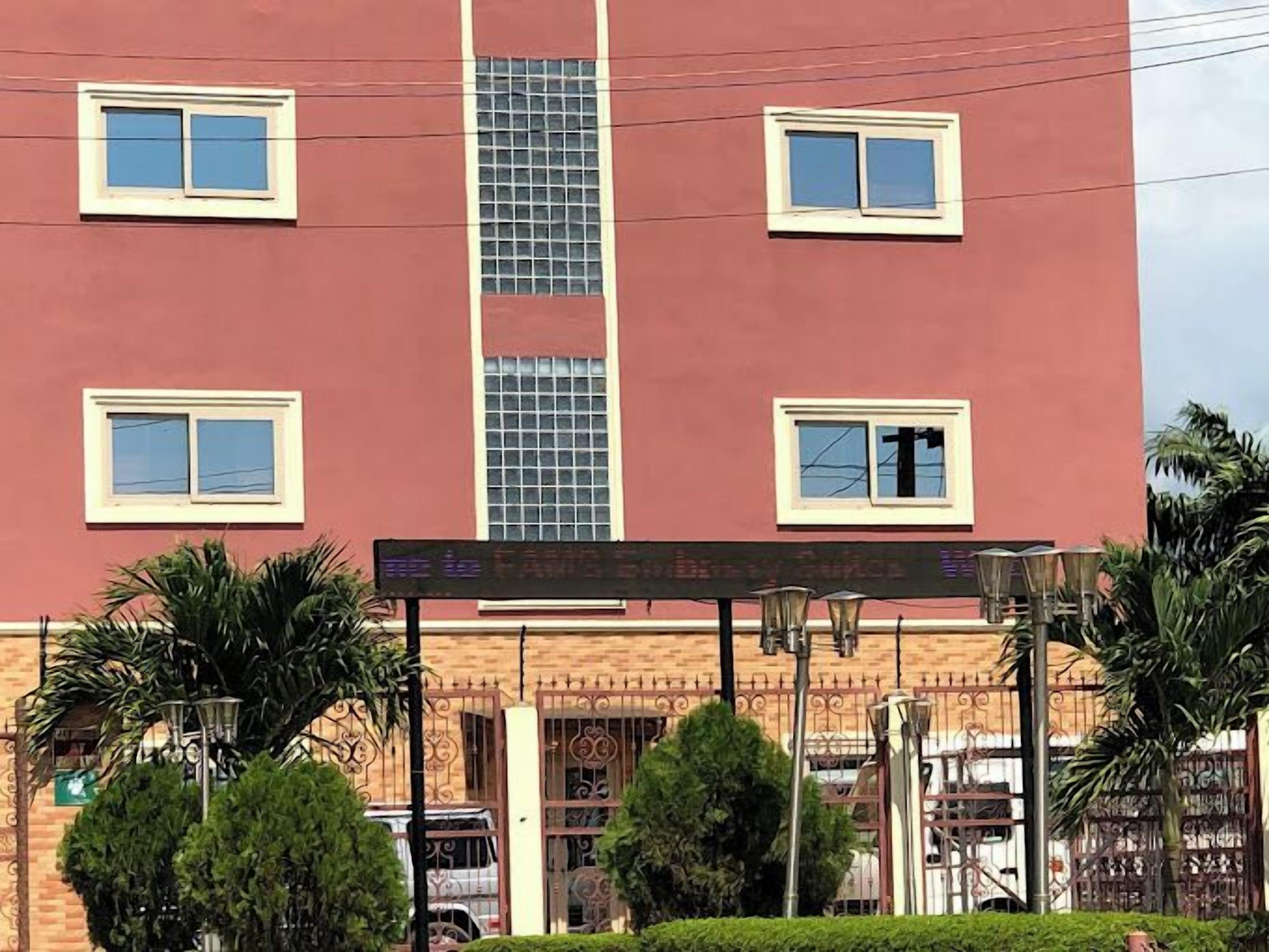 A multi-story building with a red facade, multiple windows, and a gated entrance.