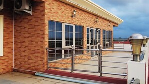 A brick building with large windows and a red carpet leading to a metal railing. - Fams Embassy Suites (Badagry)