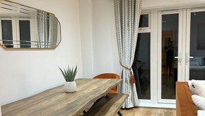 Un comedor moderno con una mesa de madera y bancos, una planta en maceta y sillas naranjas.