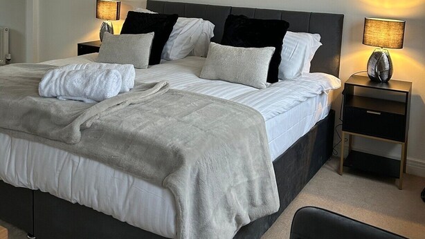 Un dormitorio moderno con una cama grande, dos mesitas de noche y una obra de arte en la pared.
