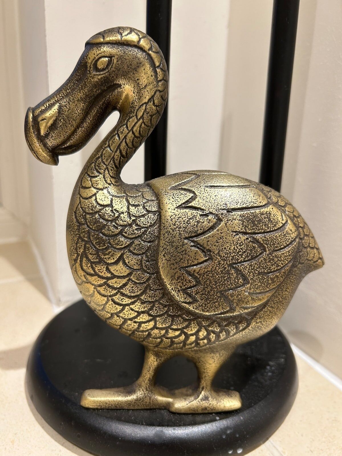 A bronze swan sculpture with detailed scales and a curved neck, standing on a black base.