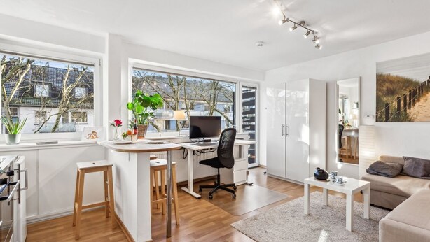 Un salon moderne avec un plancher en bois, un canapé blanc, une petite table basse et un bureau avec un ordinateur.