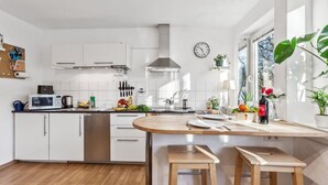 Une cuisine moderne avec des meubles blancs, une hotte en acier inoxydable et un îlot central en bois doté de tabourets.