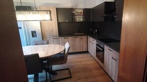 Une cuisine moderne avec des meubles en bois, un plan de travail noir et un four encastré.