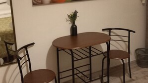 A dining area with a table and two chairs, a painting of flowers on the wall, and a small vase with a plant. - A stone's throw from the center (Salerno)