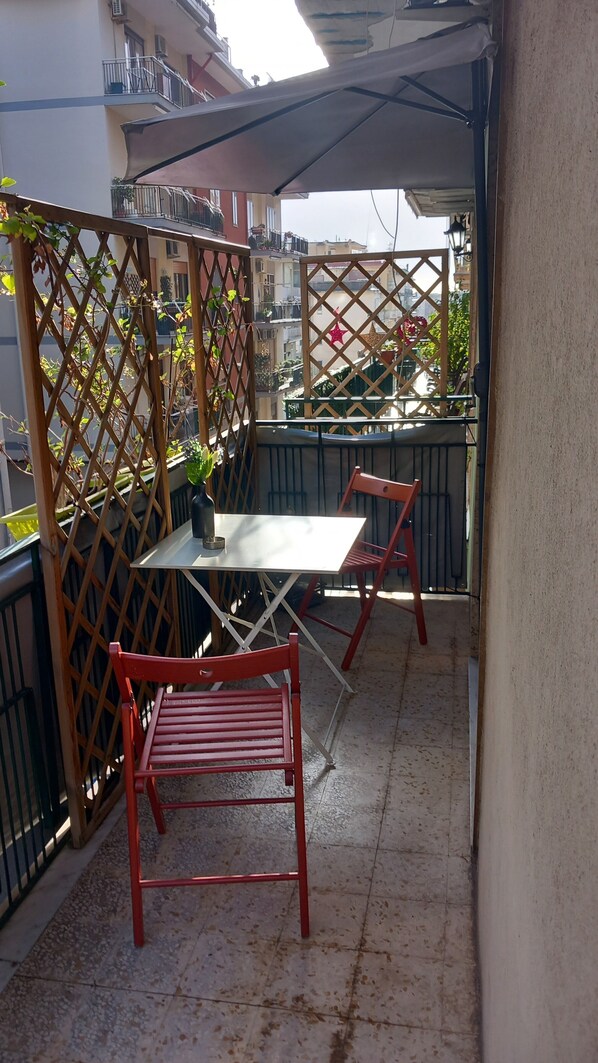 A balcony with a table and two chairs, a potted plant, and a decorative star.