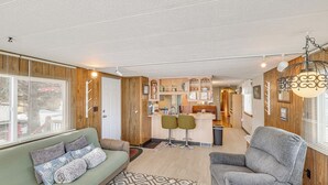 A cozy living area with a sofa, a patterned rug, and a dining area with two bar stools. - 2 Mi to Sturgis Motorcycle Rally: Peaceful Home (Sturgis)