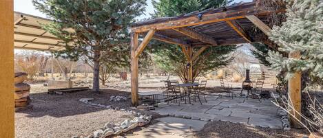 A covered patio area with stone flooring, wooden pergola, and outdoor furniture.