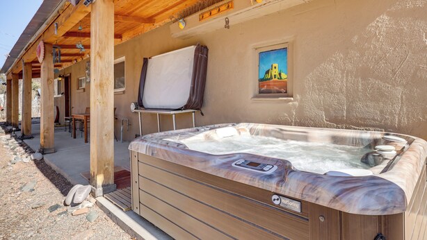 A hot tub with a wooden exterior and a wooden ceiling, located outdoors with a patio area and a painting on the wall. - Artsy Studio w/ Patio: 25 Mi to Santa Fe (Espanola)