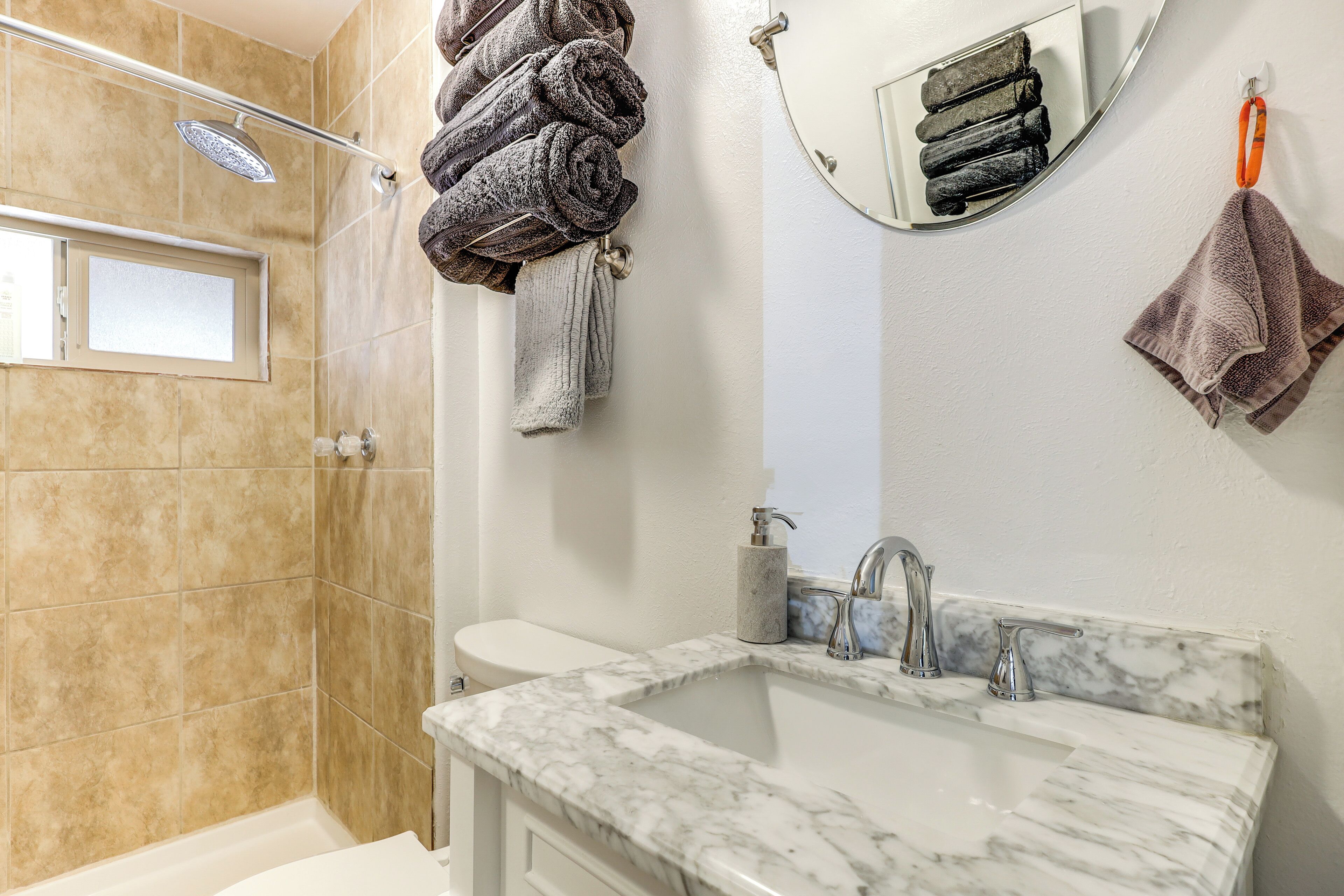 A bathroom with a shower, toilet, and sink with marble countertops.