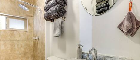 A bathroom with a shower, toilet, and sink with marble countertops.