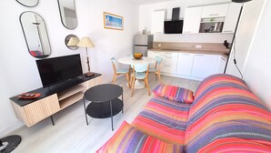 Ein modernes Wohnzimmer mit Sofa, Fernseher und Essbereich.