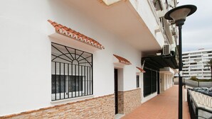 Un pasillo con piso de baldosas, una ventana con rejas y una farola.